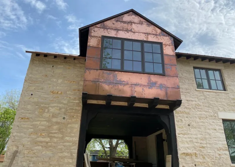 Copper metal panel facade on a stone building for Roof Repair in Cameron