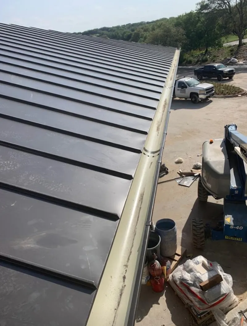 Standing seam panel and gutter detail on a metal roofing jobsite in Cameron